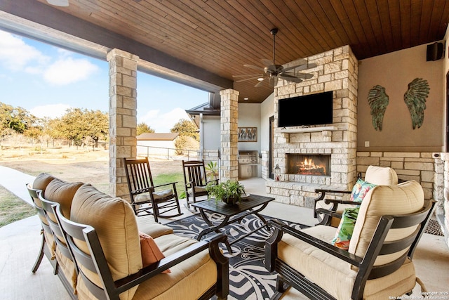 view of patio / terrace with ceiling fan and an outdoor living space with a fireplace