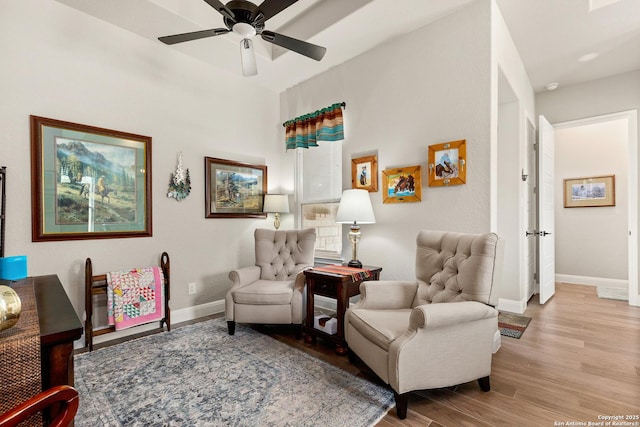 living area with baseboards, ceiling fan, and wood finished floors