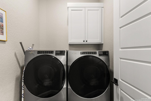 laundry room featuring a textured wall, cabinet space, and washer and clothes dryer