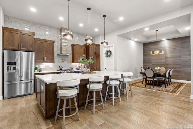 kitchen featuring light wood-style floors, baseboards, a large island, light countertops, and high end refrigerator