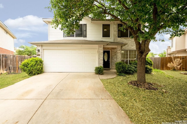 traditional-style house with an attached garage, fence, driveway, and brick siding