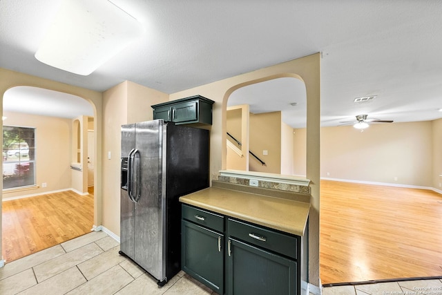 kitchen featuring ceiling fan, arched walkways, light tile patterned floors, refrigerator with ice dispenser, and visible vents