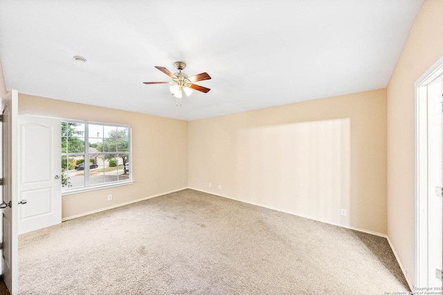 carpeted empty room with baseboards and a ceiling fan