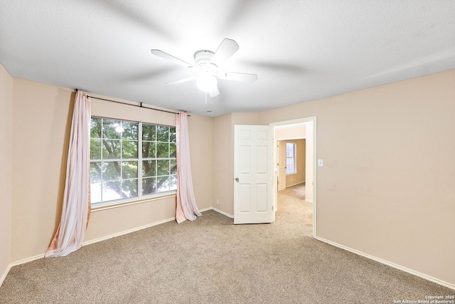 empty room featuring plenty of natural light, carpet, ceiling fan, and baseboards