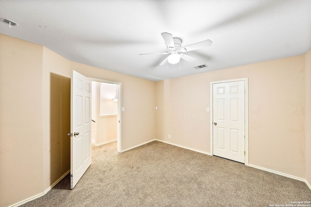 carpeted empty room with visible vents, baseboards, and ceiling fan