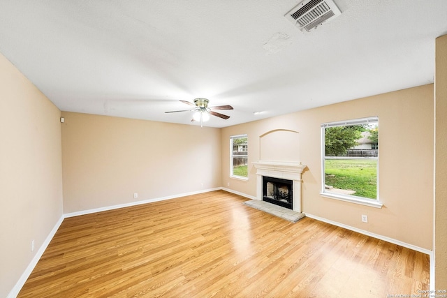 unfurnished living room with visible vents, a ceiling fan, light wood-style floors, and a wealth of natural light