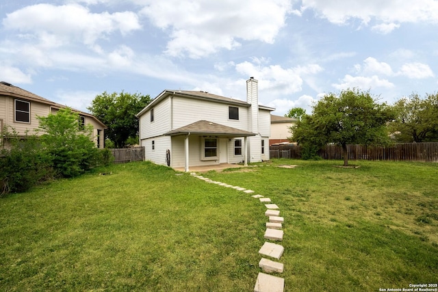 rear view of house featuring a fenced backyard, a chimney, a lawn, and a patio area
