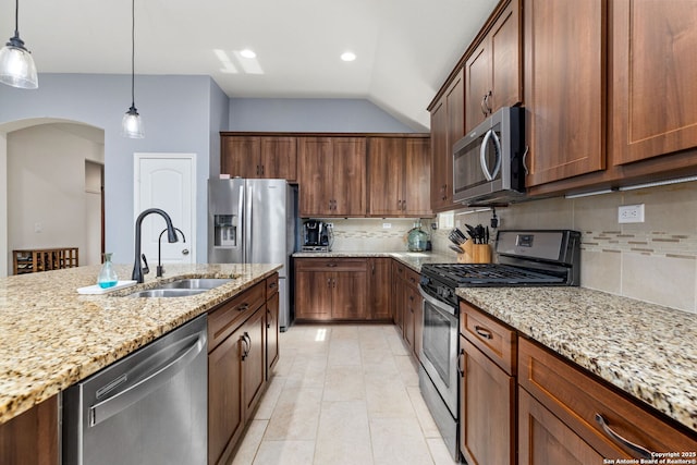 kitchen featuring stainless steel appliances, light stone countertops, a sink, and tasteful backsplash