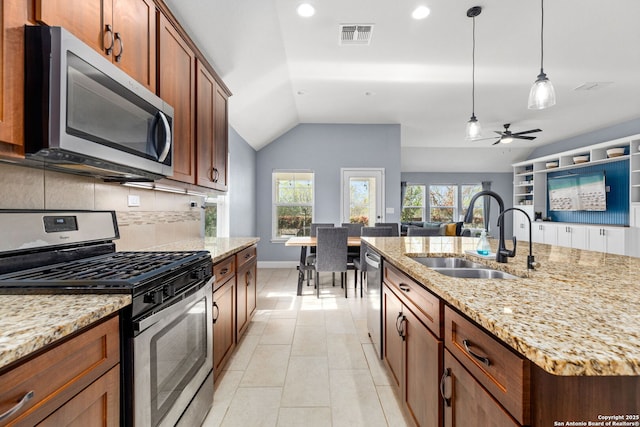 kitchen with hanging light fixtures, appliances with stainless steel finishes, a sink, lofted ceiling, and backsplash