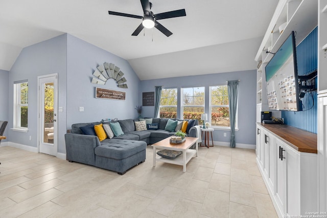 living area with baseboards, ceiling fan, and vaulted ceiling