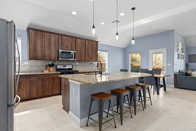 kitchen featuring light stone countertops, appliances with stainless steel finishes, a sink, lofted ceiling, and visible vents
