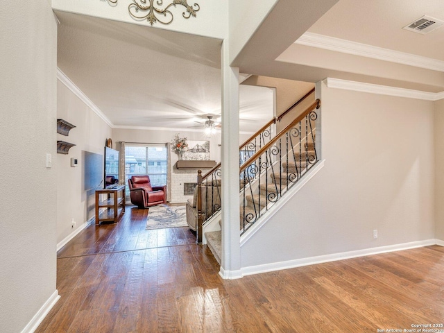 stairway with crown molding, a ceiling fan, baseboards, and wood finished floors