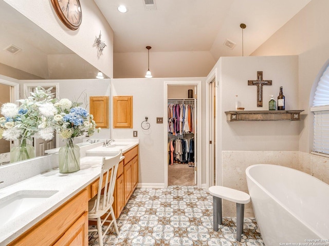 full bath featuring double vanity, a sink, a freestanding tub, and visible vents