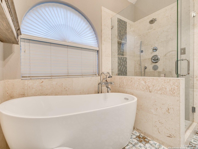 bathroom featuring a freestanding tub, tile walls, and a stall shower