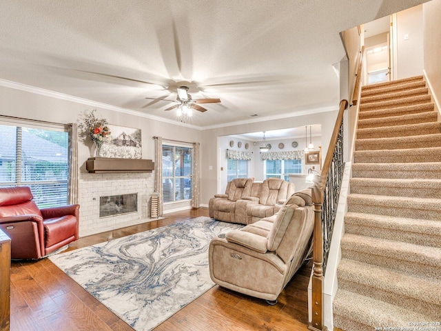 living room with a ceiling fan, wood finished floors, stairway, and a fireplace