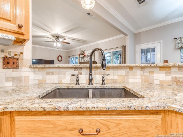 kitchen featuring light stone countertops, visible vents, decorative backsplash, and a sink