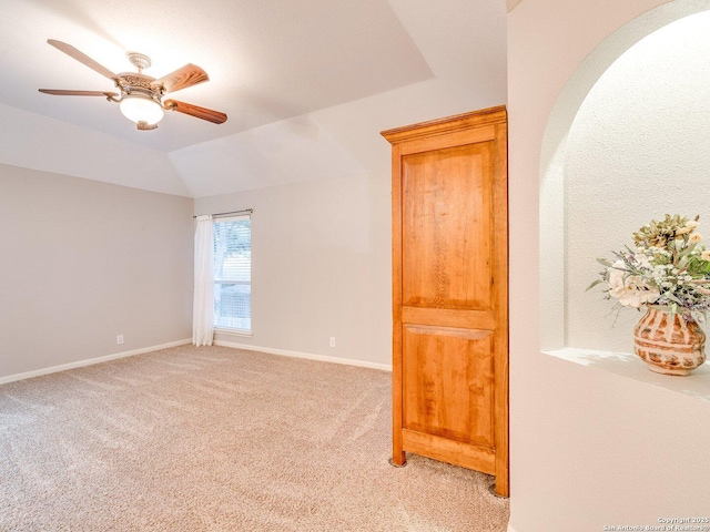 empty room featuring a ceiling fan, baseboards, light carpet, and lofted ceiling