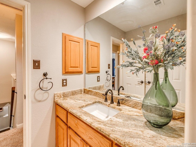 bathroom with vanity, a textured wall, and visible vents