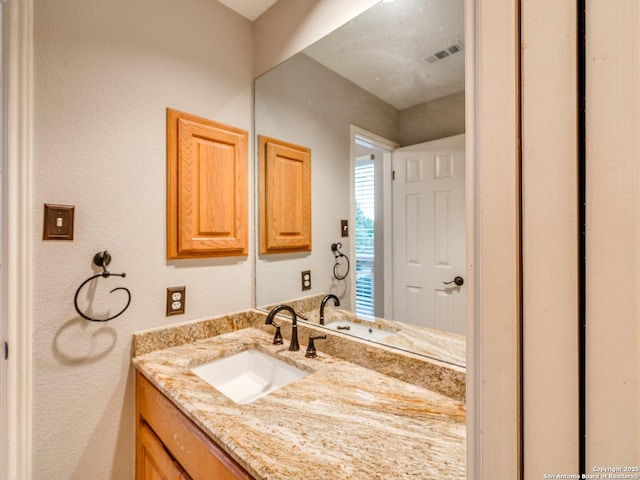 bathroom featuring vanity, a textured wall, and visible vents