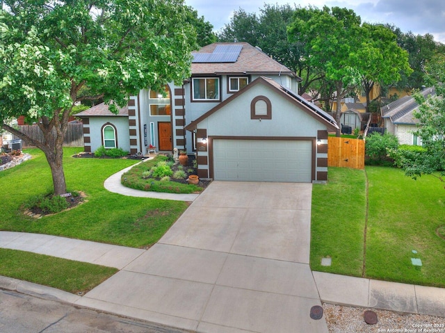 traditional-style house featuring concrete driveway, a front lawn, fence, and solar panels