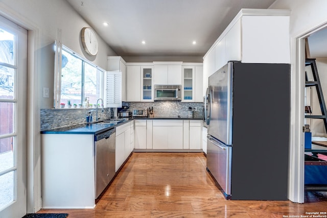 7731 Broadway Unit I-42, San Antonio, TX 78209 - kitchen featuring dark countertops, a sink, stainless steel appliances, tasteful backsplash, and glass insert cabinets