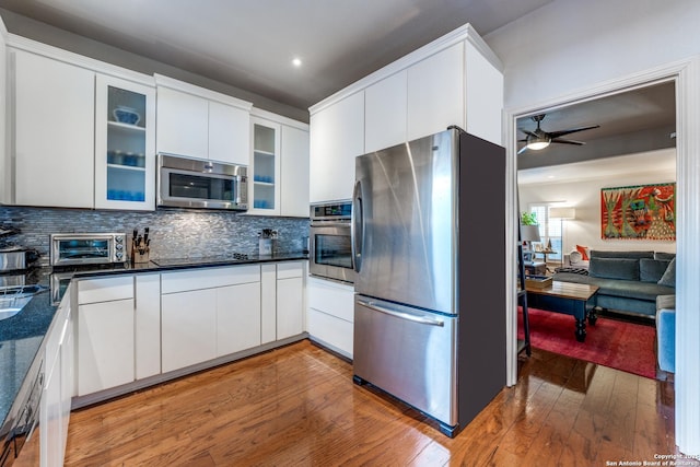 7731 Broadway Unit I-42, San Antonio, TX 78209 - kitchen with stainless steel appliances, dark countertops, glass insert cabinets, and light wood-style flooring