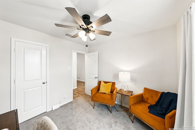 living area with carpet floors, ceiling fan, visible vents, and baseboards