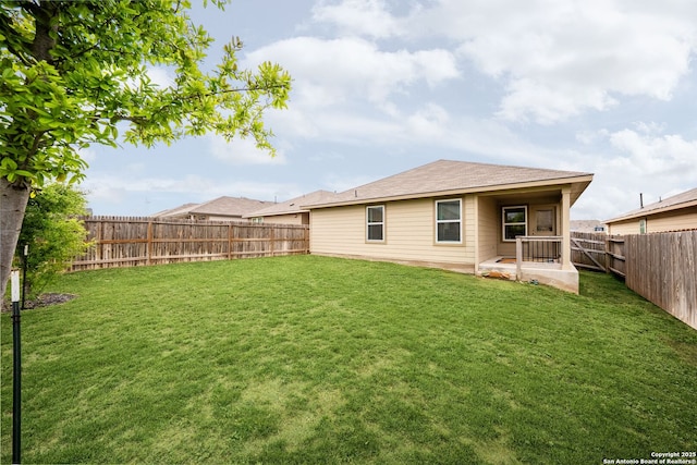 rear view of house with a lawn, a fenced backyard, and a patio