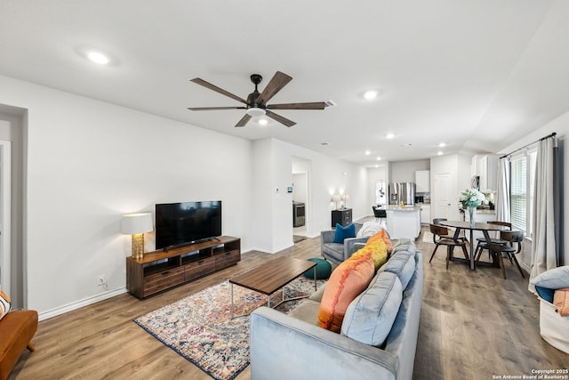living area featuring baseboards, ceiling fan, recessed lighting, and light wood-style flooring