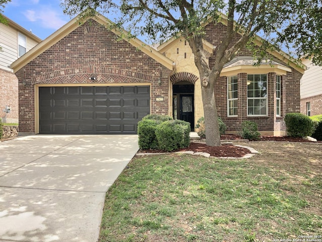 view of front of home featuring an attached garage, concrete driveway, a front lawn, and brick siding