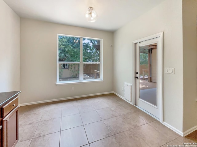 unfurnished dining area with baseboards and light tile patterned floors