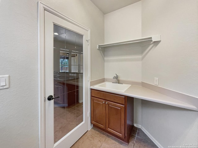 interior space with light tile patterned flooring, baseboards, and a sink