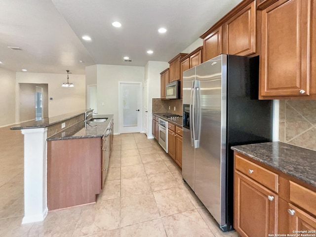kitchen featuring decorative backsplash, brown cabinets, a sink, appliances with stainless steel finishes, and light tile patterned floors