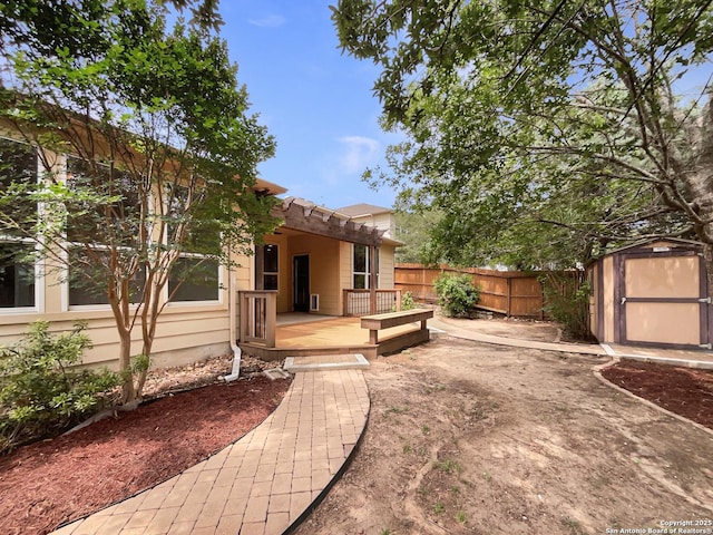 view of yard featuring fence, a storage unit, an outdoor structure, and a deck