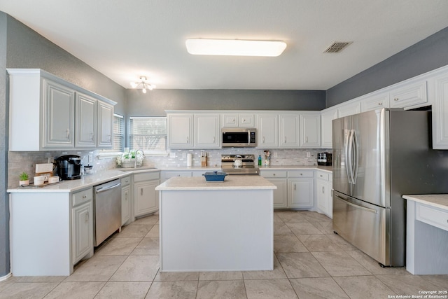 kitchen featuring a sink, appliances with stainless steel finishes, tasteful backsplash, and a center island