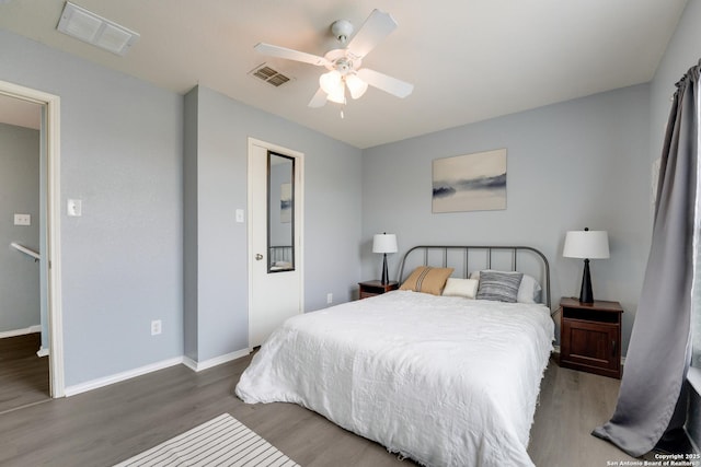 bedroom with baseboards, wood finished floors, and visible vents