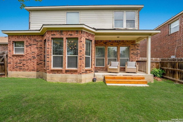back of property with a lawn, brick siding, and a fenced backyard