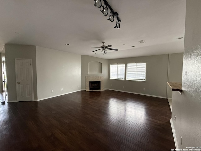 unfurnished living room featuring wood finished floors, a ceiling fan, a tile fireplace, and visible vents