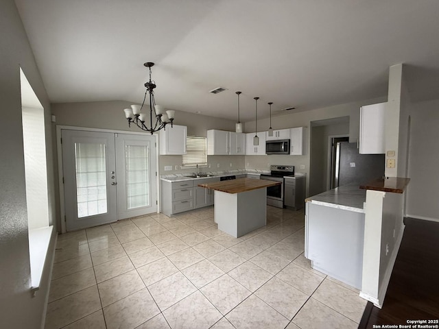 kitchen featuring appliances with stainless steel finishes, an inviting chandelier, a sink, a kitchen island, and visible vents