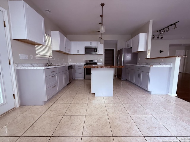 kitchen featuring appliances with stainless steel finishes, a center island, a sink, light tile patterned floors, and gray cabinetry