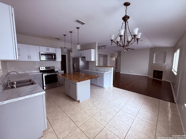 kitchen with open floor plan, a tile fireplace, a sink, a notable chandelier, and stainless steel appliances