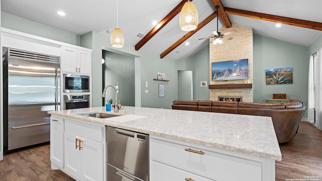 kitchen featuring ceiling fan, a sink, dark wood-style floors, open floor plan, and built in appliances