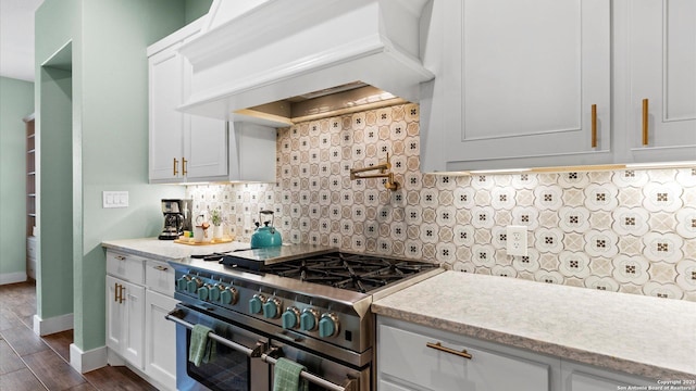 kitchen with decorative backsplash, range with two ovens, premium range hood, baseboards, and dark wood-type flooring