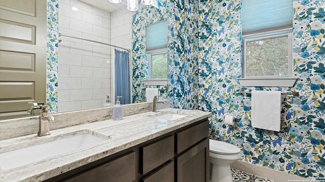 full bath with double vanity, a sink, and toilet