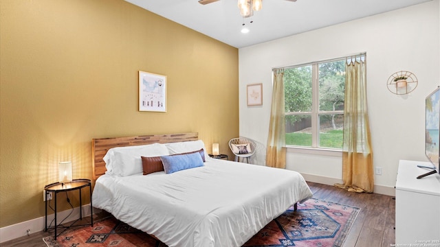 bedroom featuring a ceiling fan, baseboards, multiple windows, and wood finished floors