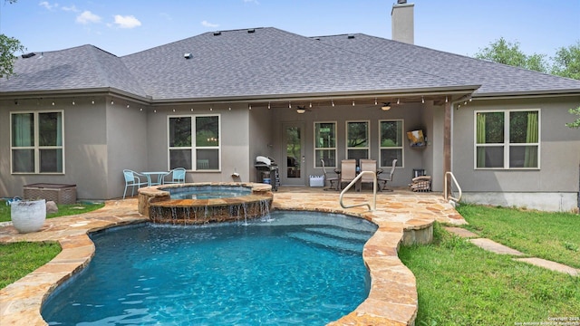 rear view of property with ceiling fan, roof with shingles, stucco siding, an outdoor pool, and an in ground hot tub