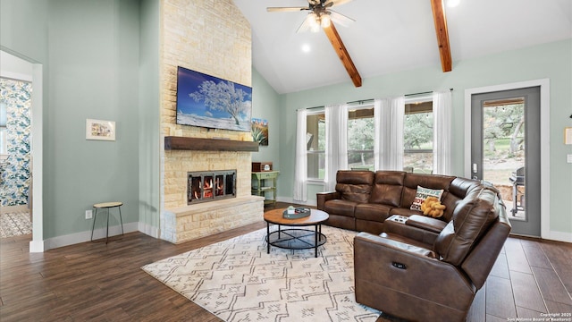 living area featuring a stone fireplace, baseboards, ceiling fan, and wood finished floors