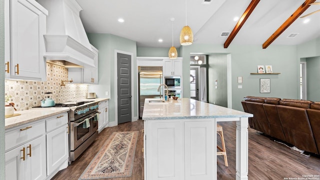 kitchen featuring decorative backsplash, dark wood-style flooring, open floor plan, premium range hood, and appliances with stainless steel finishes