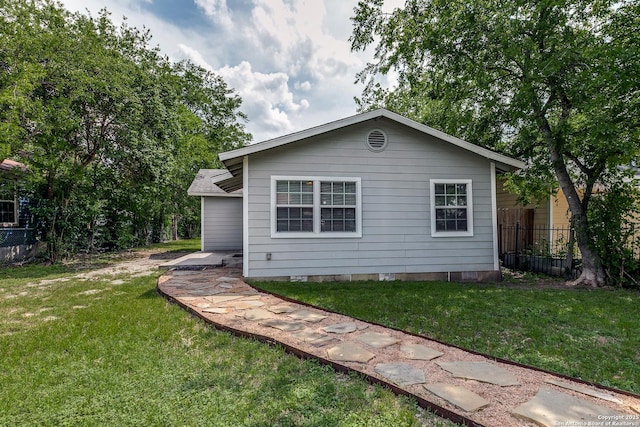 back of property with a lawn, fence, and crawl space