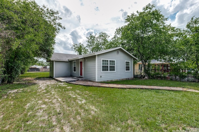 rear view of property featuring fence and a yard